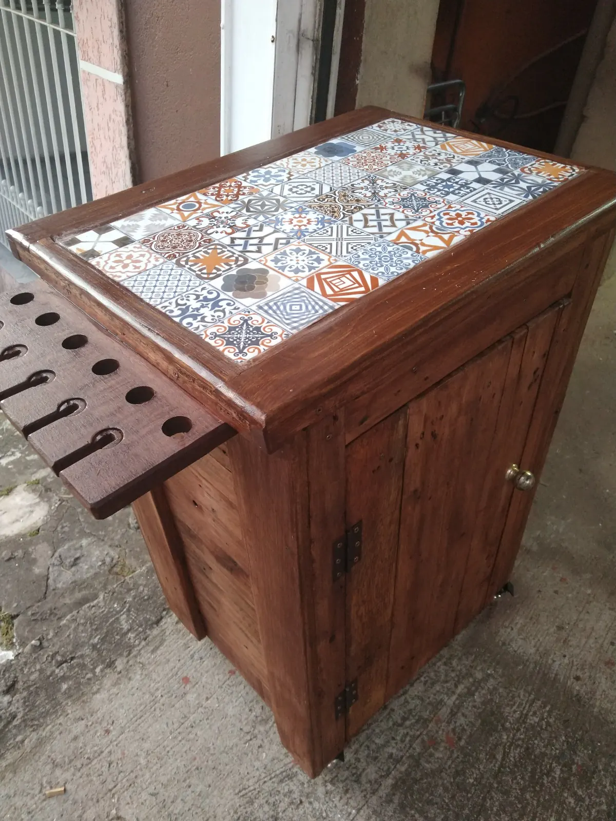 Carrinho-bar de madeira com tampo de azulejos estampados e suporte para taças