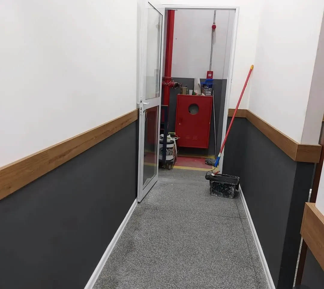 Corredor com parede cinza na metade de baixo e rodameio de madeira até a porta