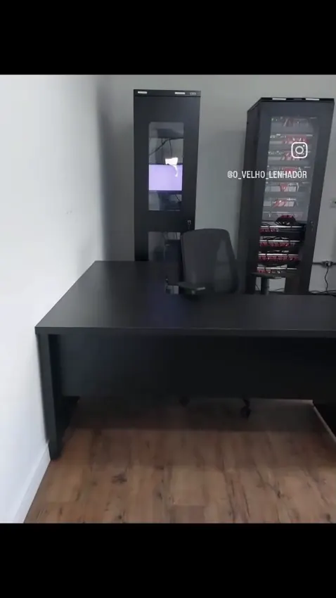 Escritório com mesa escura, cadeiras e armários de vidro