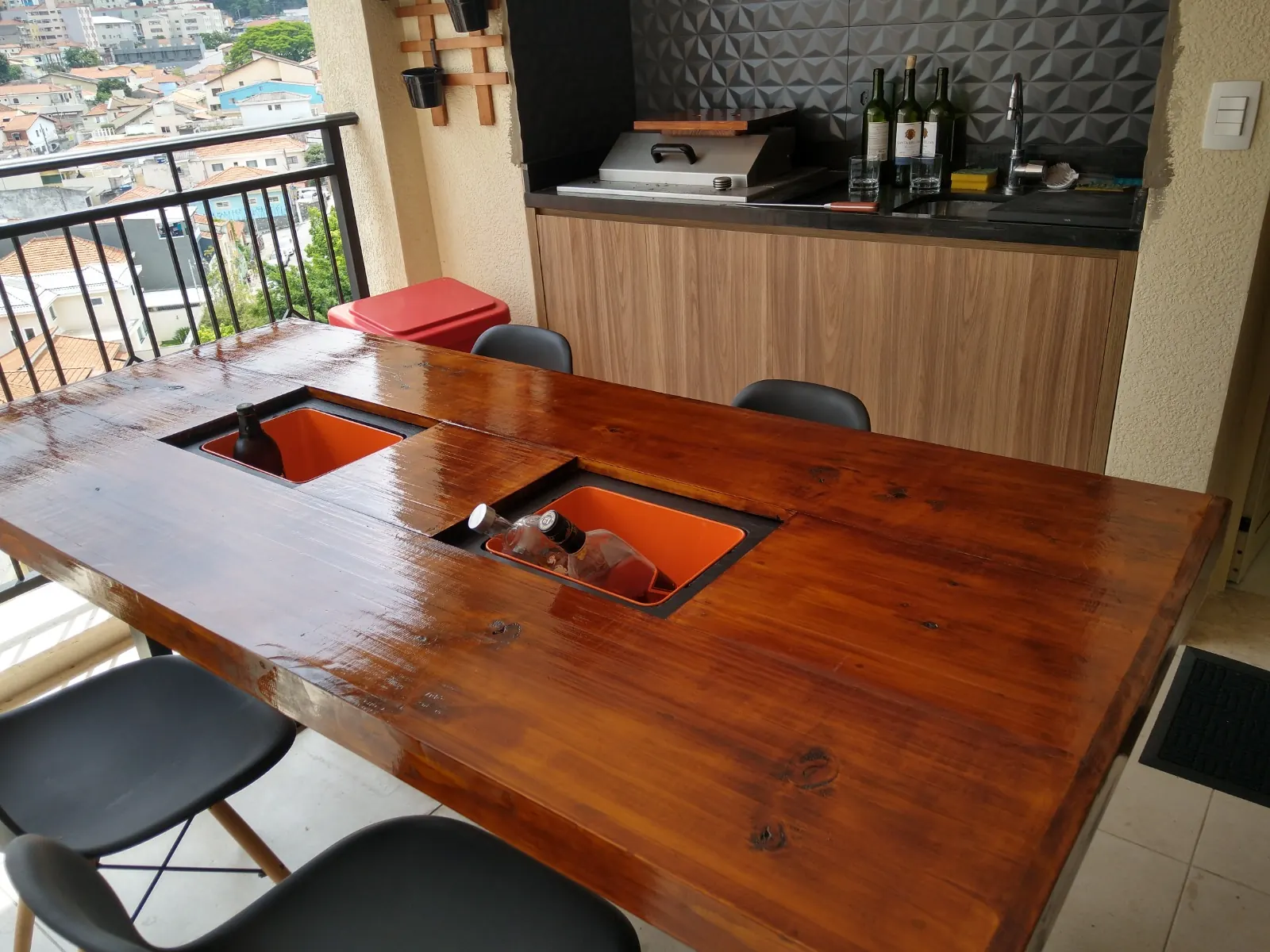 Mesa de madeira com dois coolers embutidos no tampo, em varanda gourmet