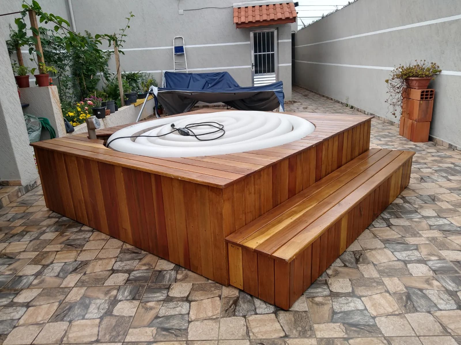 Ofurô com deck de madeira e degrau largo em quintal com plantas