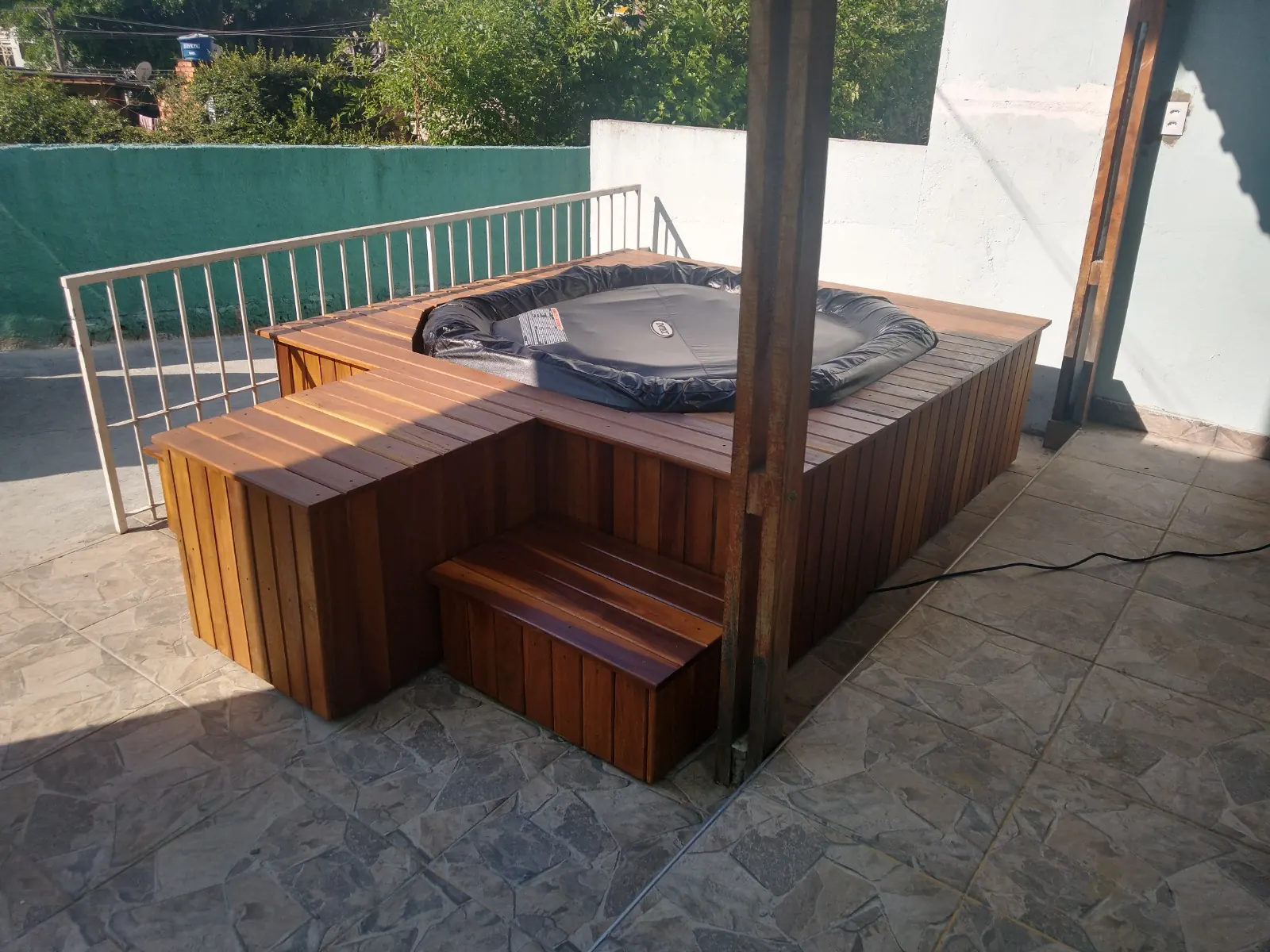 Ofurô com deck de madeira e escada em área externa com pergolado