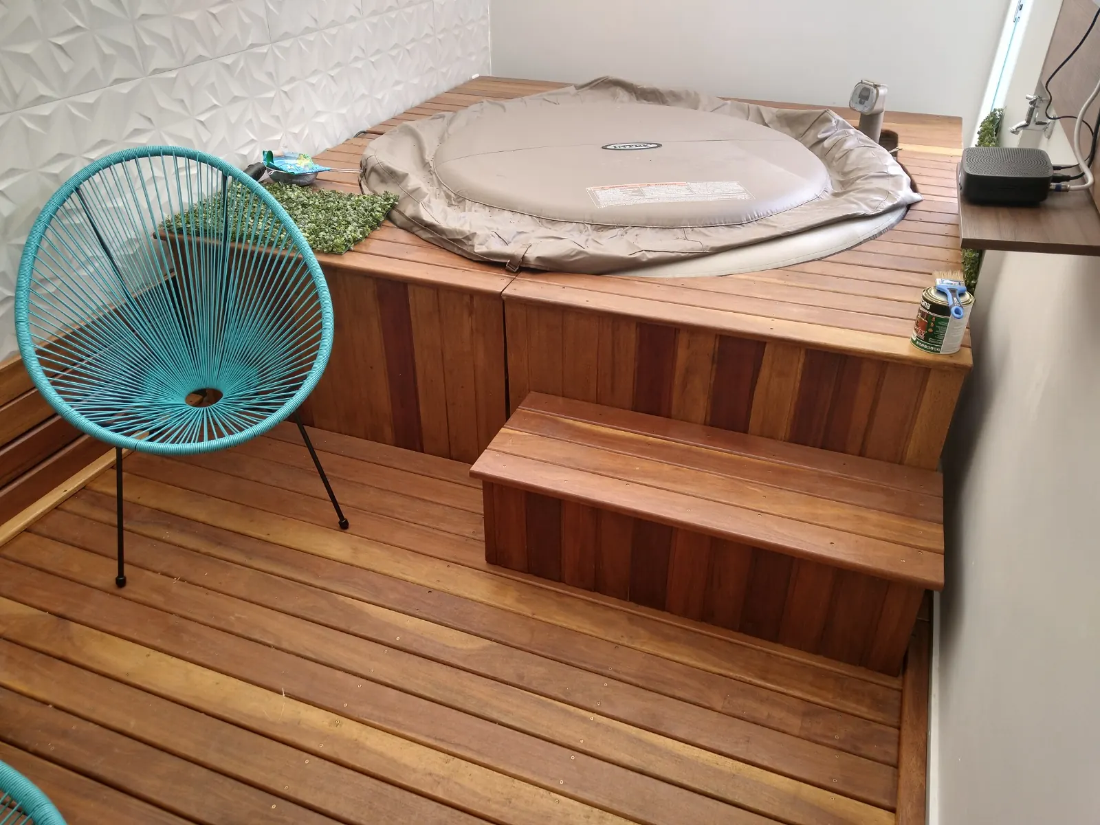 Ofurô com deck de madeira e degrau em varanda com cadeira azul